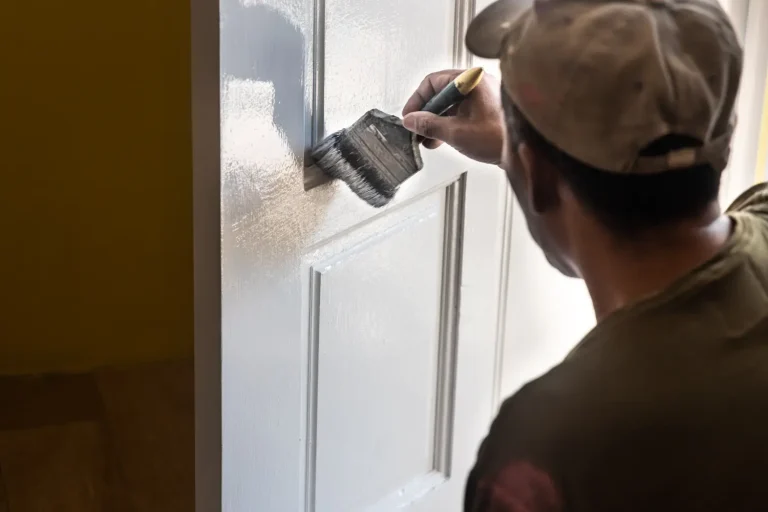 Exterior painting Airdrie shows a person carefully painting a door with a brush