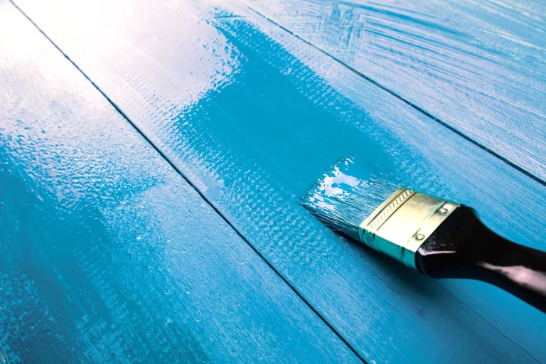 A paintbrush glides over a freshly coated blue surface